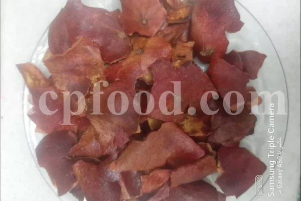 Bulk pomegranate peel for export shown as dried red rind pieces on a glass plate